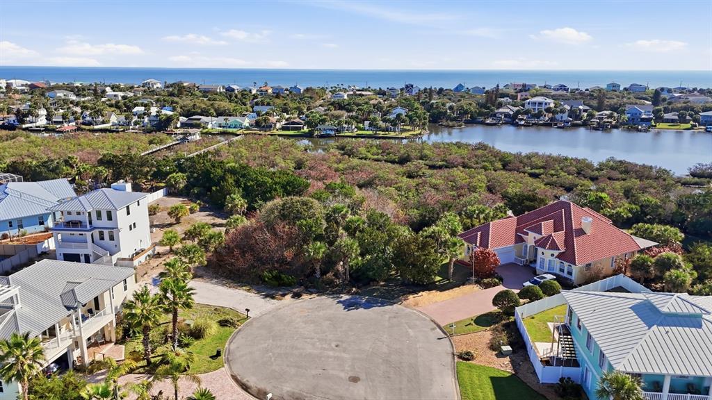An aerial view shows a cul-de-sac surrounded by houses, dense vegetation, and a nearby waterway — 570 SPRINGDALE DRIVE, FLAGLER BEACH, FL