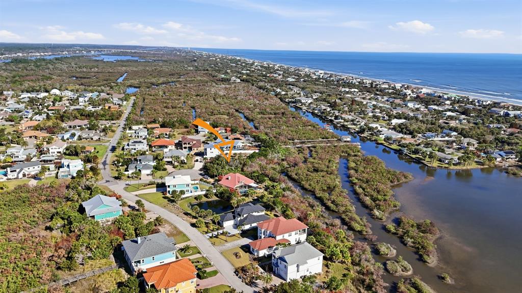 An aerial view shows a coastal neighborhood with houses, marshland, and a nearby ocean beach — 570 SPRINGDALE DRIVE, FLAGLER BEACH, FL