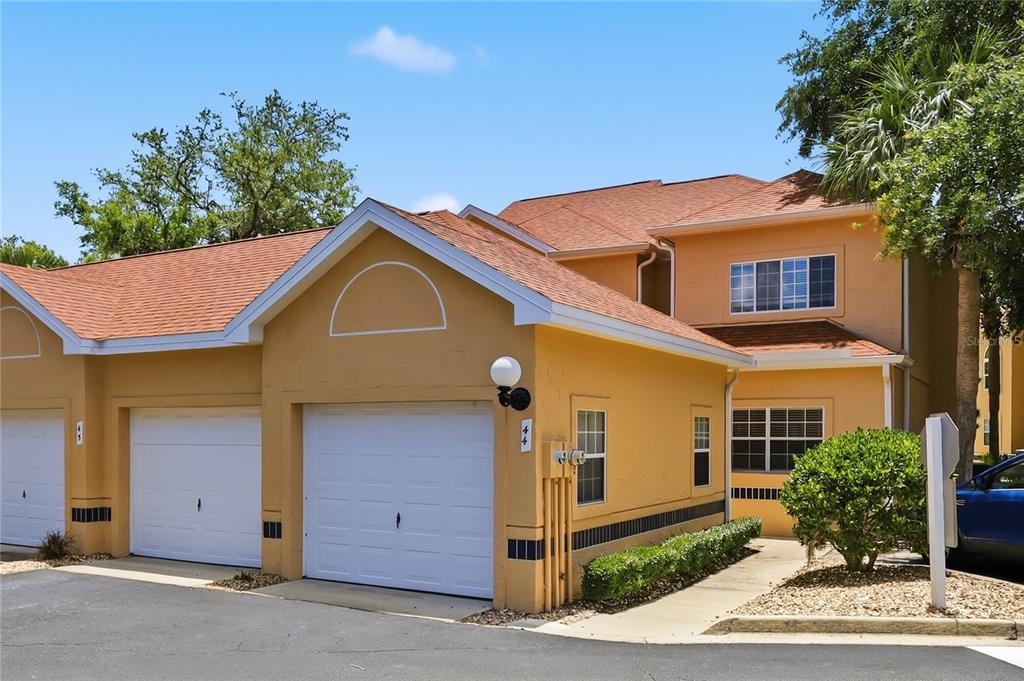 A two-story tan building with two white garage doors and a shingled roof — 44 CAPTAINS WALK, PALM COAST, FL