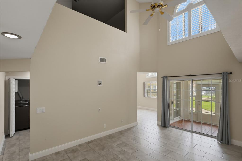 A living room with high ceilings, tile flooring, a ceiling fan, and sliding glass doors — 44 CAPTAINS WALK, PALM COAST, FL