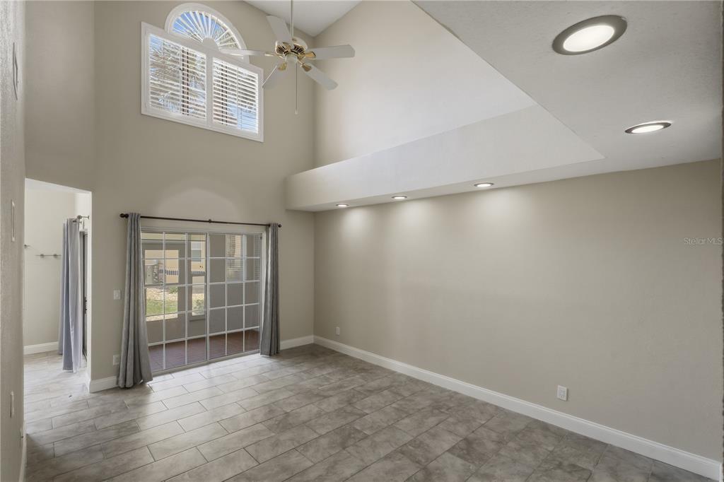 A living room with high ceilings, tile flooring, recessed lighting, and sliding glass doors — 44 CAPTAINS WALK, PALM COAST, FL