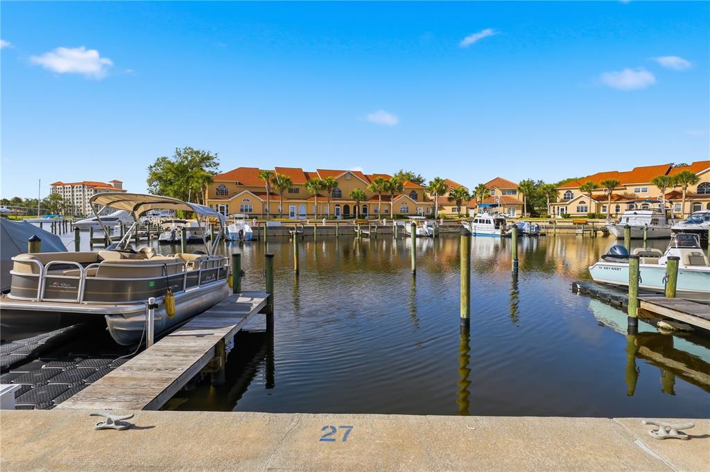 A boat is docked at a pier in front of waterfront residential buildings — 44 CAPTAINS WALK, PALM COAST, FL