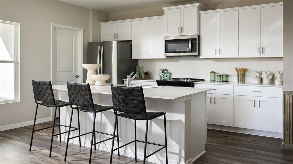 A modern kitchen features white cabinets, stainless steel appliances, a center island, and black barstools — 9170 BENT BRANCH, DADE CITY, FL