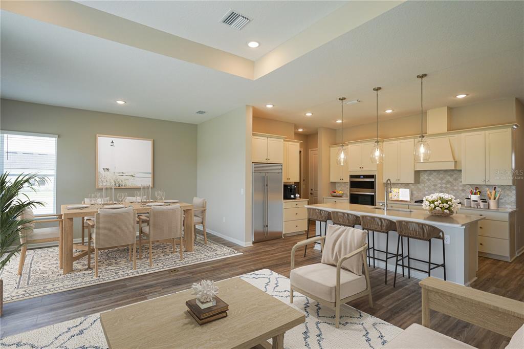 An open-concept kitchen and dining area features light cabinetry, stainless steel appliances, and wood flooring — 282 KNOTTED BIRCH AVENUE, ST AUGUSTINE, FL