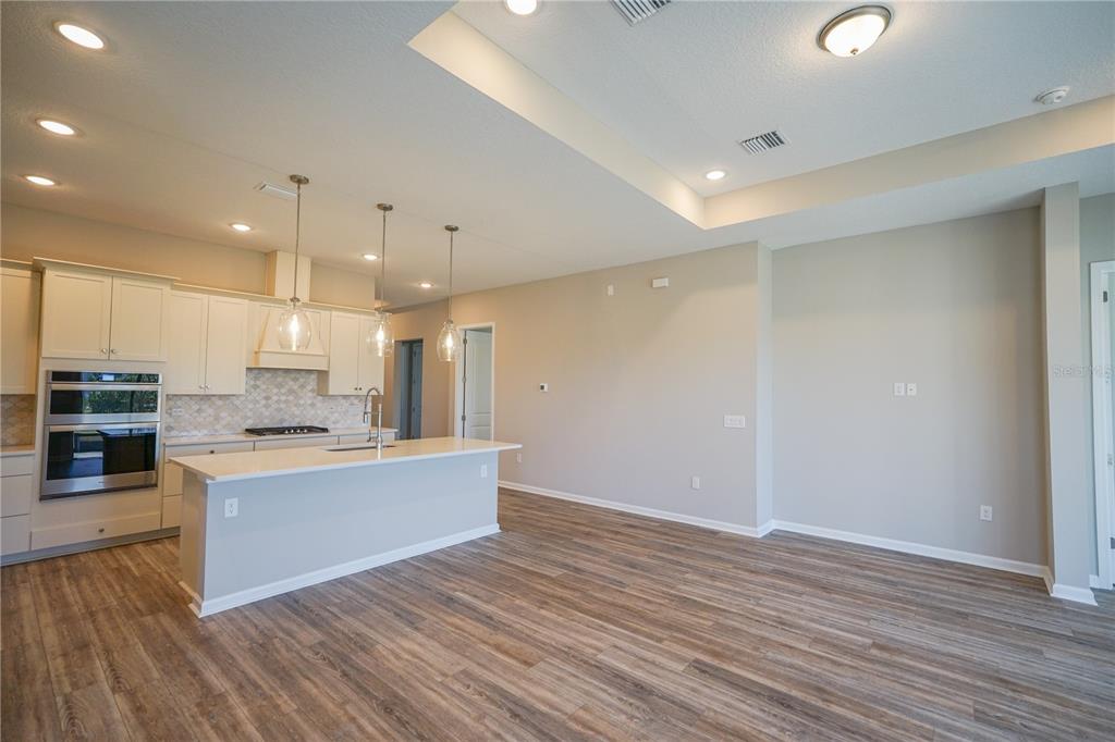 A kitchen with white cabinets, a center island, and wood-look flooring in an open space — 282 KNOTTED BIRCH AVENUE, ST AUGUSTINE, FL