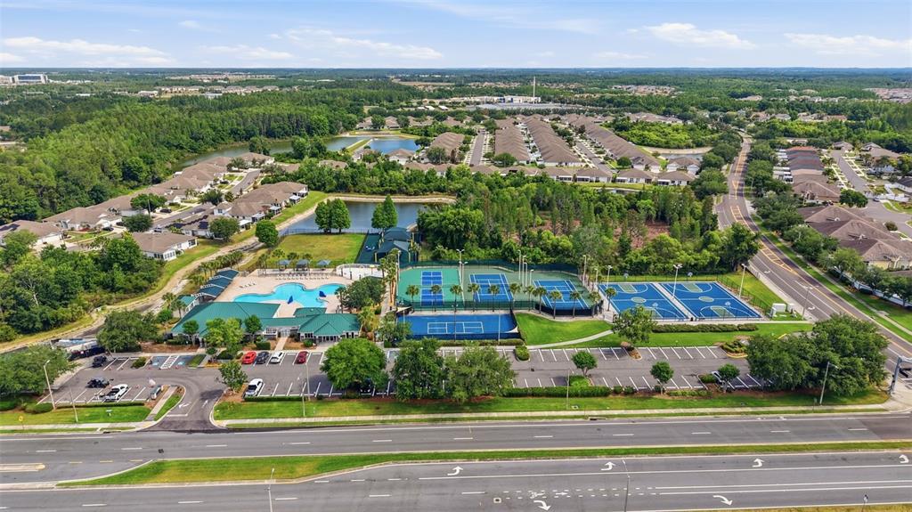 An aerial view shows a community clubhouse with a swimming pool and several tennis courts — 1902 ECHO POND PLACE, WESLEY CHAPEL, FL