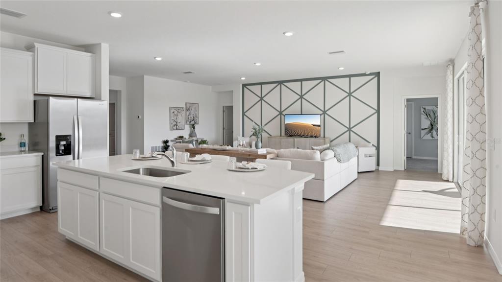 A kitchen island with a stainless steel dishwasher faces a living area with accent wall — 12760 NW 17TH PLACE, NEWBERRY, FL