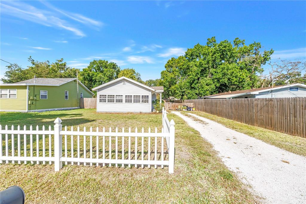 A white house with a gravel driveway and a white picket fence under a blue sky — 3012 17TH STREET E, BRADENTON, FL