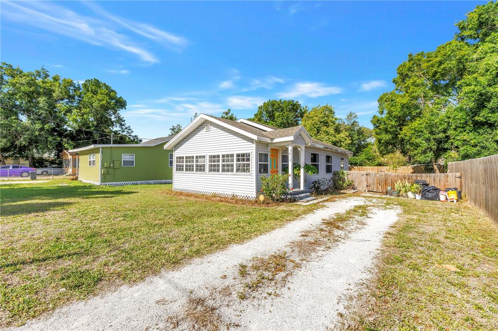 A light-gray house with a gravel driveway and a green neighboring home in the background — 3012 17TH STREET E, BRADENTON, FL