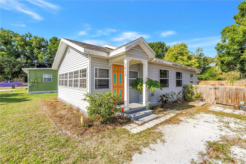 A single-story house with light gray siding, a bright orange front door, and a porch — 3012 17TH STREET E, BRADENTON, FL
