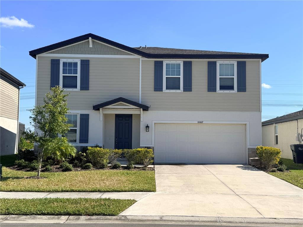 A two-story suburban house features beige siding, blue shutters, and a two-car garage — 10062 DAYBREAK GLEN, PARRISH, FL