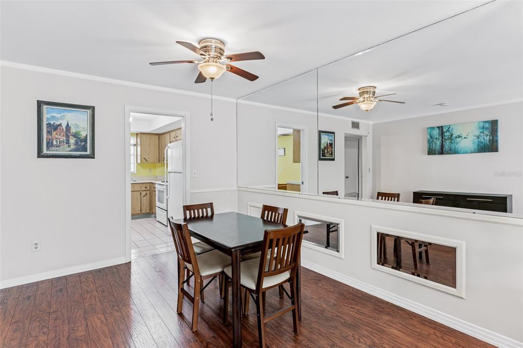 A dining area with a dark wood table, chairs, wood flooring, and mirrored wall panels — 147 BLUFF VIEW DRIVE UNIT 206, BELLEAIR BLUFFS, FL