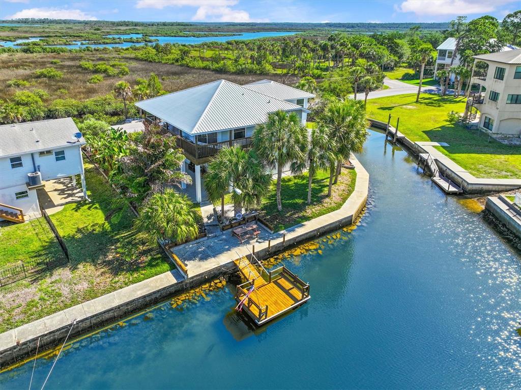 An aerial view shows a house with a metal roof, a wooden dock, and palm trees — 3532 EAGLE NEST DRIVE, HERNANDO BEACH, FL