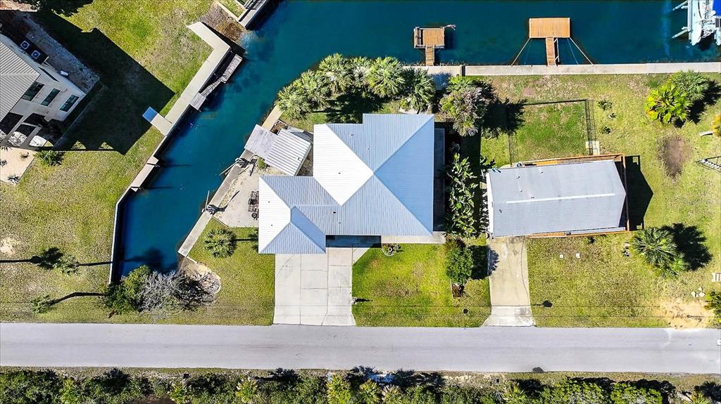 An aerial view shows a house with a metal roof, a driveway, and a canal — 3532 EAGLE NEST DRIVE, HERNANDO BEACH, FL