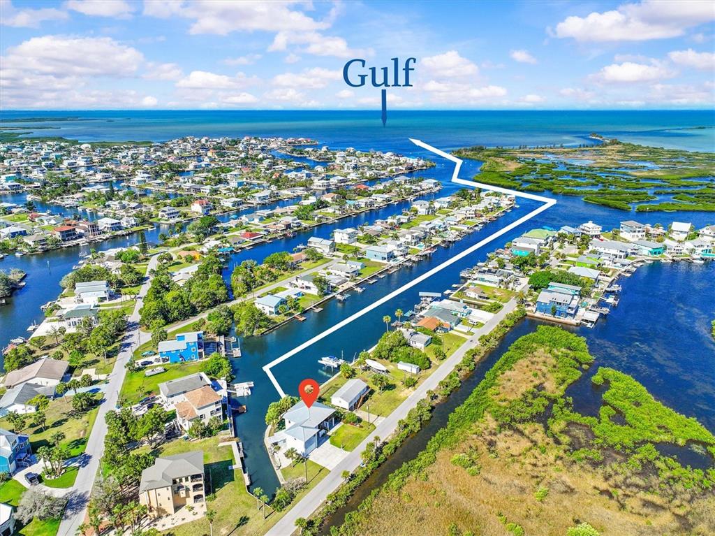 An aerial view shows a waterfront house with a canal leading toward the Gulf — 3532 EAGLE NEST DRIVE, HERNANDO BEACH, FL