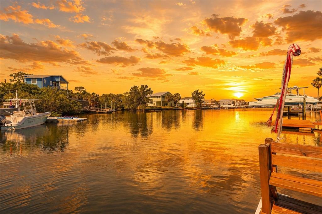 A view of a canal at sunset with houses, docks, and boats along the water — 3532 EAGLE NEST DRIVE, HERNANDO BEACH, FL