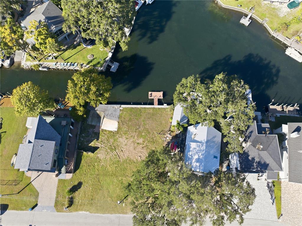 An aerial view shows a vacant waterfront lot situated between two houses with a dock — 0 CIRCLE DRIVE, WEEKI WACHEE, FL