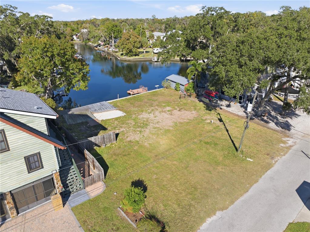 An aerial view shows a vacant waterfront lot situated between a house and a road — 0 CIRCLE DRIVE, WEEKI WACHEE, FL