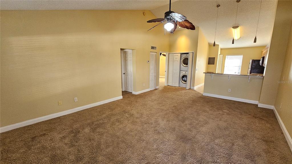 A living room with beige carpet, vaulted ceilings, a ceiling fan, and an open kitchen — 3651 N GOLDENROD ROAD UNIT C205, WINTER PARK, FL
