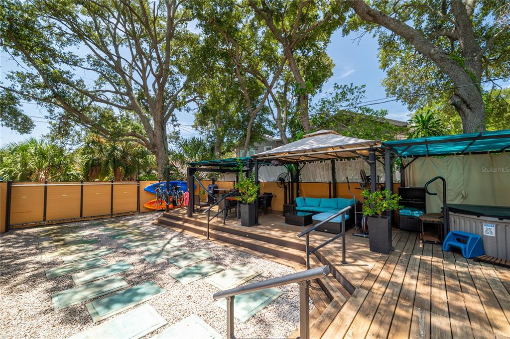 A backyard features a wooden deck with a gazebo, outdoor furniture, and a gravel patio — 7410 5TH AVENUE N, ST PETERSBURG, FL