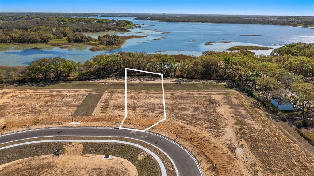 An aerial view shows a vacant residential lot outlined in white near a large lake — MARIGOLD BELLE CIRCLE, CLERMONT, FL
