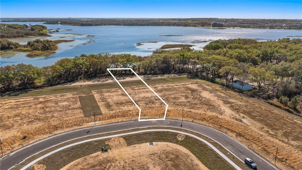 An aerial view shows a vacant residential lot outlined in white near a lake — MARIGOLD BELLE CIRCLE, CLERMONT, FL
