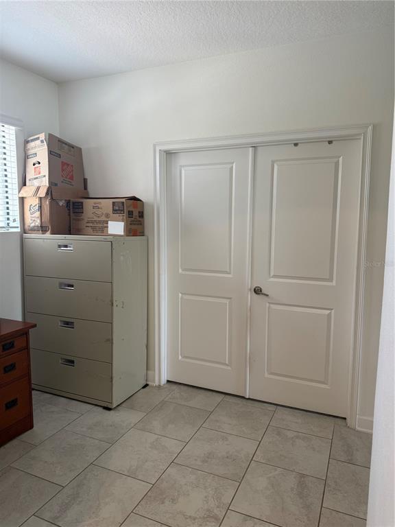 A room features a four-drawer metal filing cabinet, cardboard boxes, and double closet doors — 8990 AZALEA SANDS LANE, DAVENPORT, FL