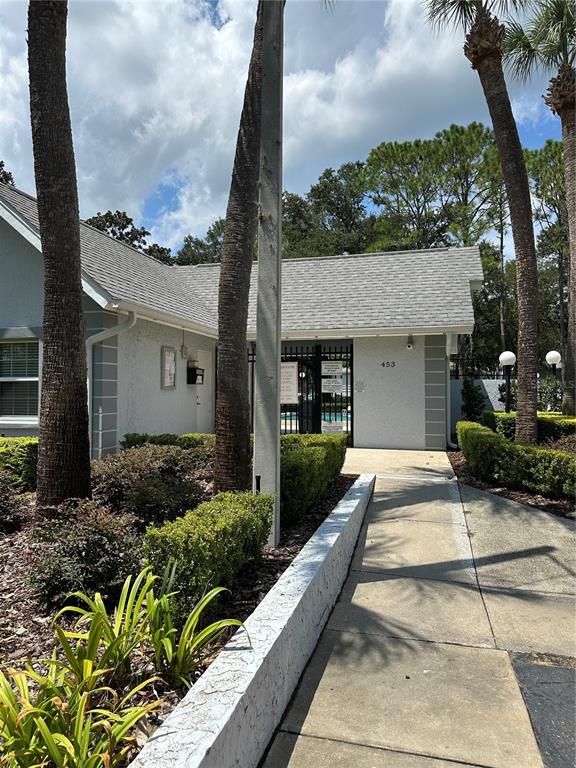 A concrete walkway leads to a building entrance with a gated pool area — 584 FAIRWAYS LANE UNIT F202, OCALA, FL