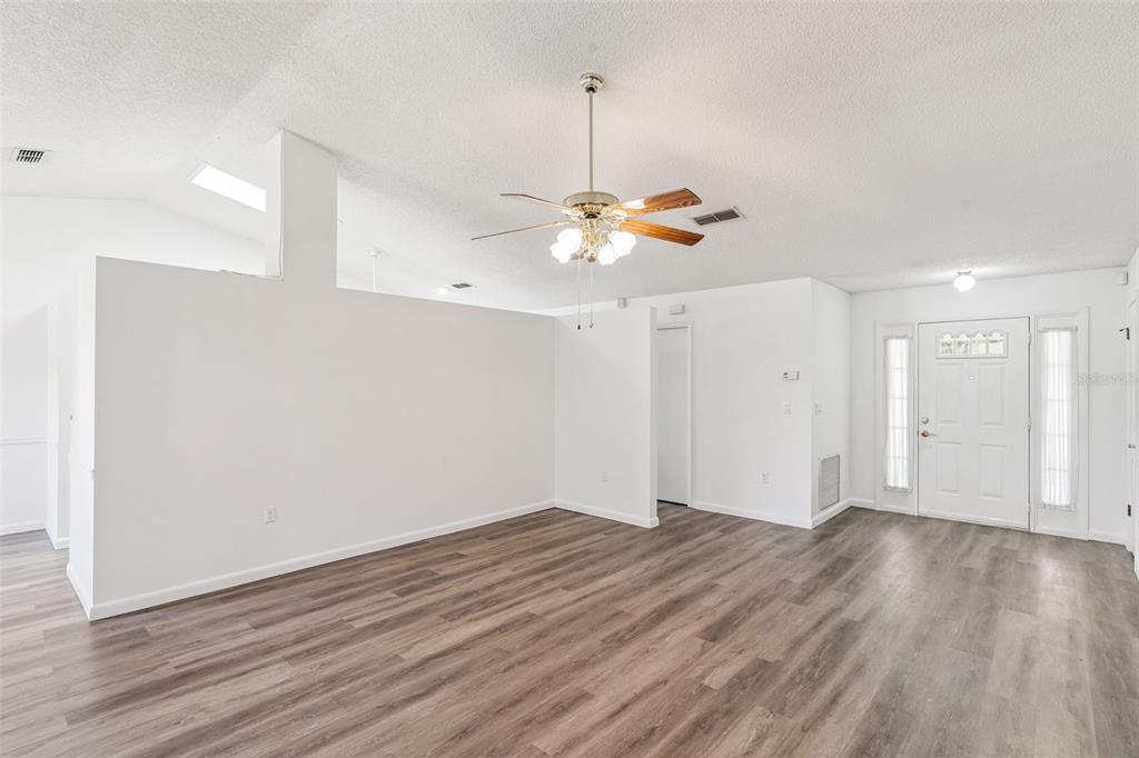 An interior view of a living room with white walls, wood-look flooring, and a ceiling fan — 1409 NEW ABBEY AVENUE, LEESBURG, FL