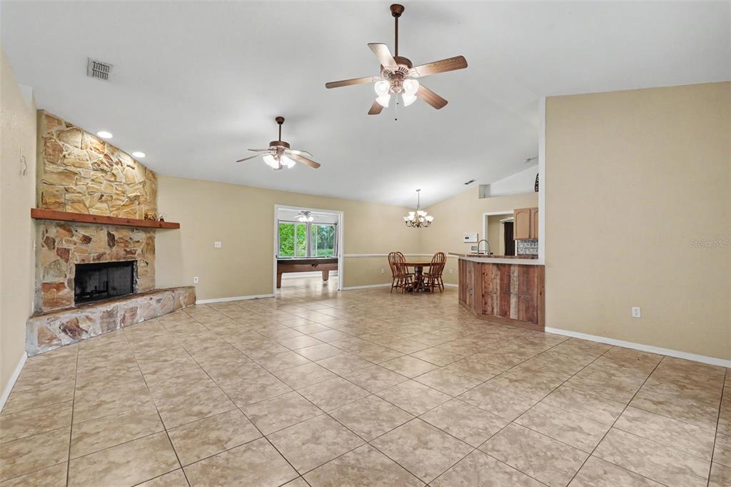 A spacious living area features tile flooring, a stone fireplace, and a kitchen breakfast bar — 4618 REOLA ROAD, DOVER, FL