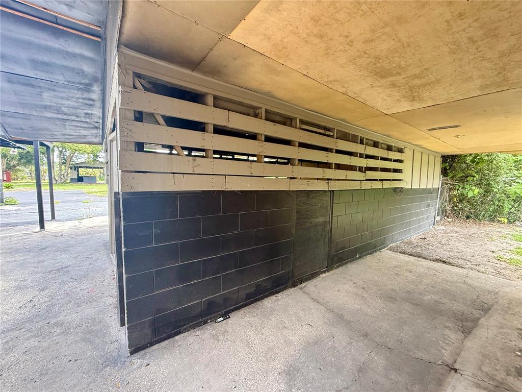 A covered outdoor area features a black concrete block wall topped with horizontal wooden slats — PALMETTO STREET, EUSTIS, FL