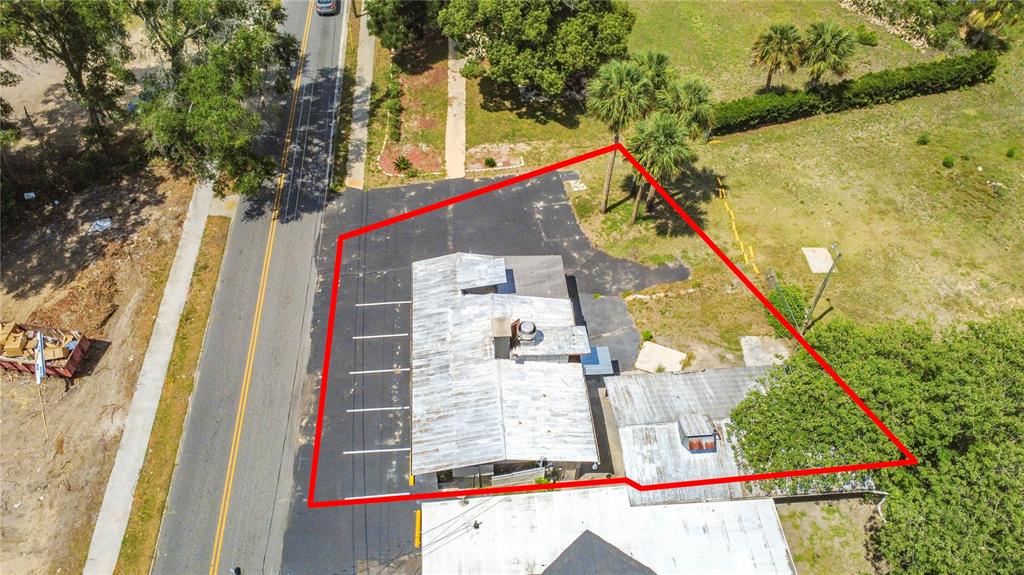 An aerial view shows a commercial building with a metal roof and adjacent parking lot — PALMETTO STREET, EUSTIS, FL