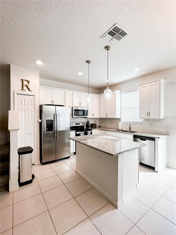 A kitchen features white cabinets, granite countertops, stainless steel appliances, and a central island — 966 E 10TH STREET, APOPKA, FL