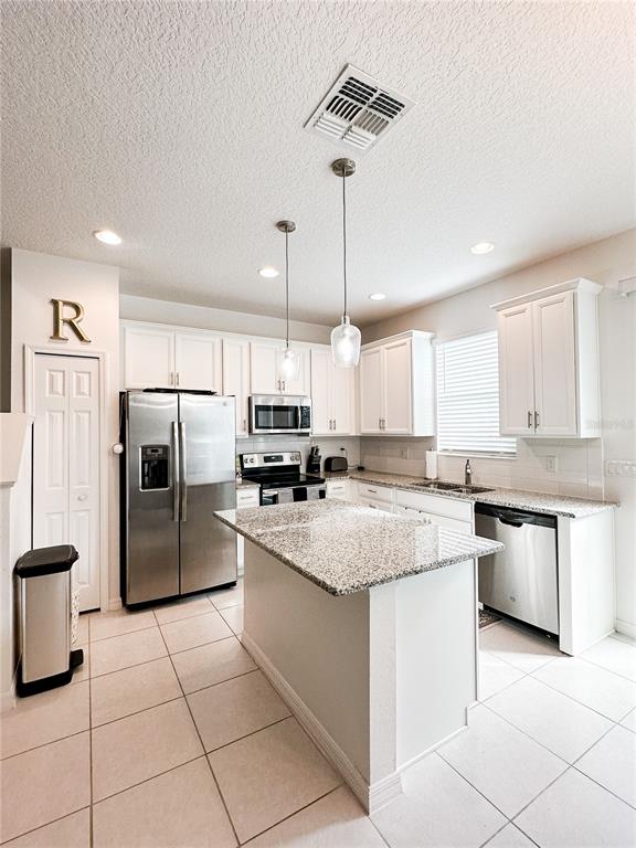 A kitchen features white cabinets, granite countertops, stainless steel appliances, and a central island — 966 E 10TH STREET, APOPKA, FL