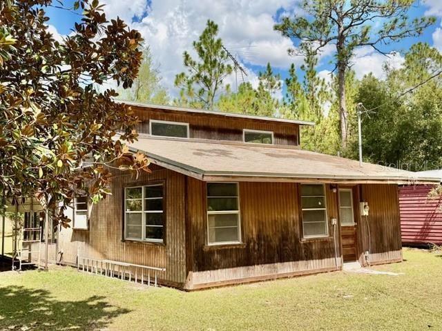 A wooden house with a metal roof and a ladder leaning against the side exterior — 4850 NW 55TH AVENUE, BELL, FL