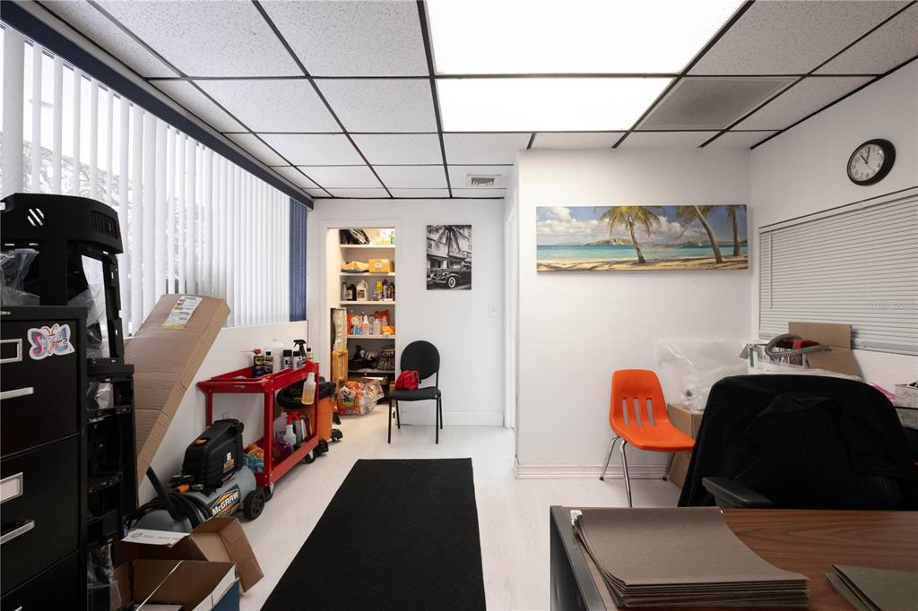 An office space features a drop ceiling, white walls, a storage closet, and scattered furniture — 1820 NE 2ND STREET, GAINESVILLE, FL