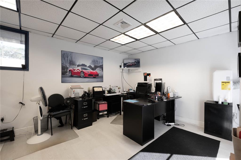 An office space features a black desk, a red sports car wall print, and white flooring — 1820 NE 2ND STREET, GAINESVILLE, FL