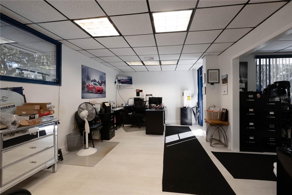 An office space features a drop ceiling, white walls, light flooring, and a black desk — 1820 NE 2ND STREET, GAINESVILLE, FL
