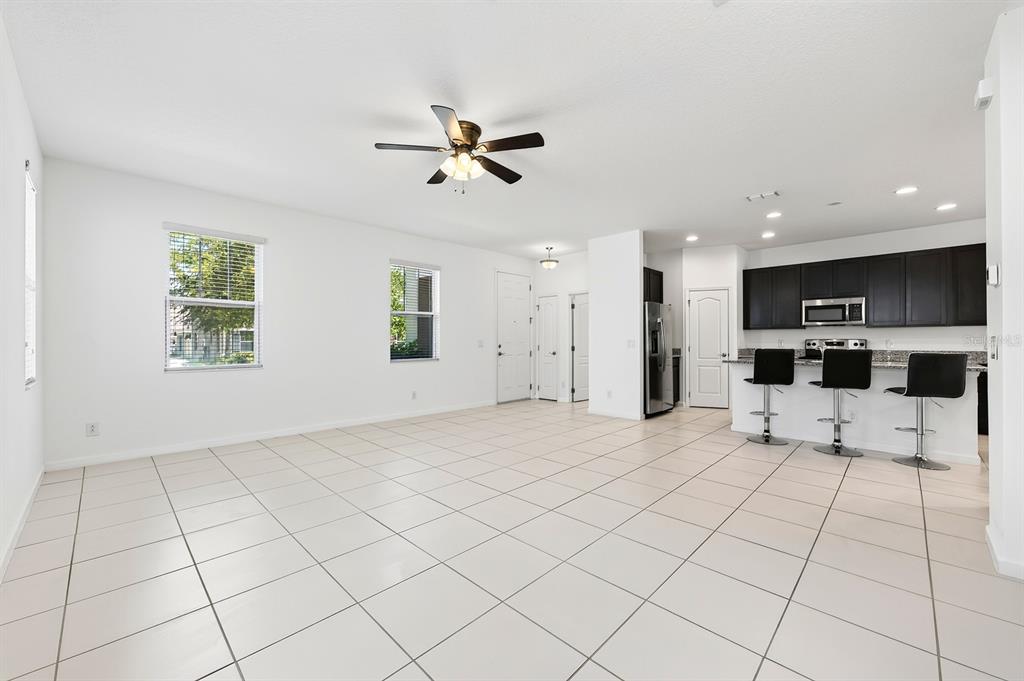 An open-concept living area features white tile floors, a ceiling fan, and a modern kitchen — 8016 SWEET ORANGE AVENUE, WINTER GARDEN, FL