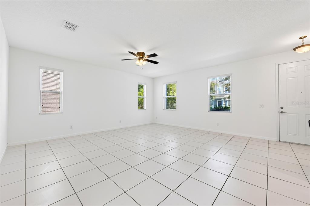 An empty room with white walls, white tile flooring, a ceiling fan, and several windows — 8016 SWEET ORANGE AVENUE, WINTER GARDEN, FL