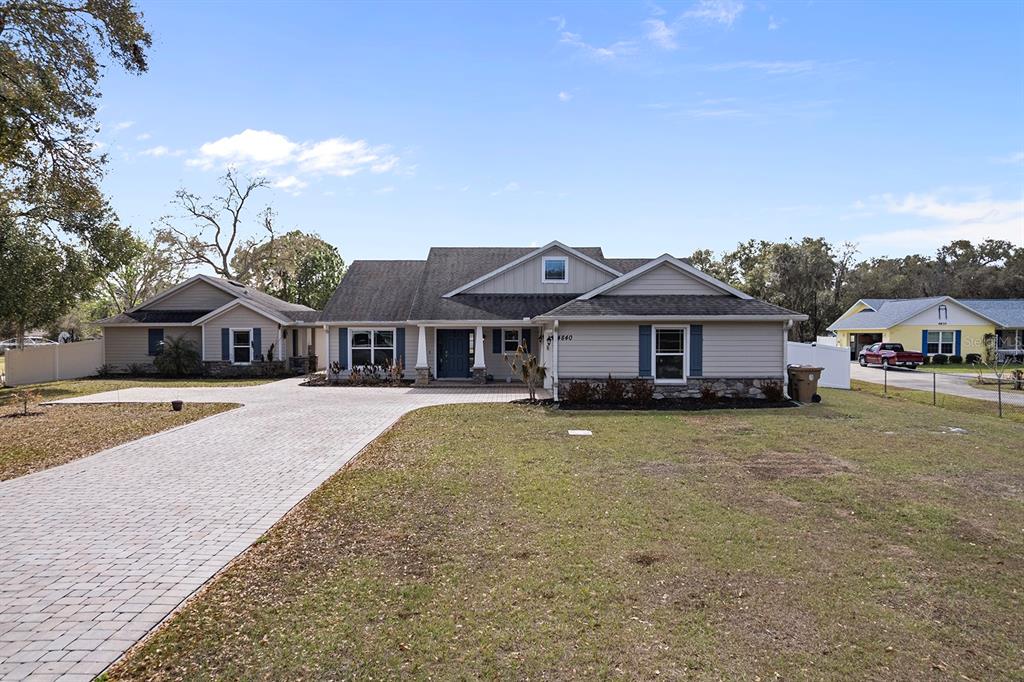 A single-story house with light siding, a stone facade, and a paved driveway — 4840 OLD OAK TRAIL, ST CLOUD, FL