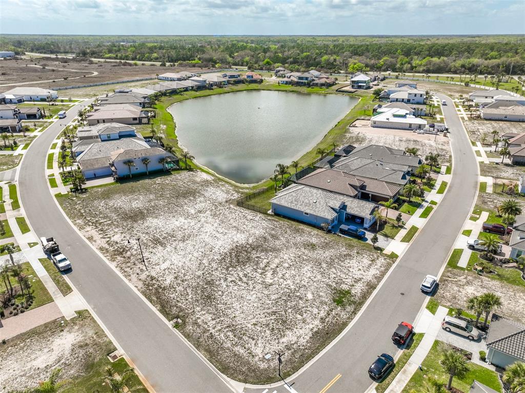 An aerial view shows a vacant residential lot situated between two suburban streets and a pond — 1 DEL PALMA DRIVE, PALM COAST, FL