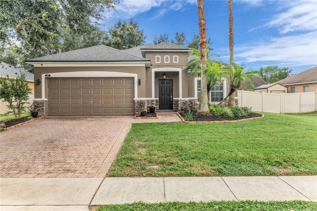 A single-story house with a brown stucco exterior, a two-car garage, and a paved driveway — 847 AYDEN OAK LANE, OCOEE, FL