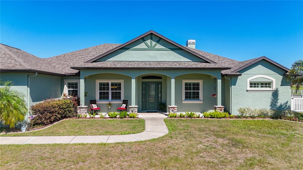 A single-story house with a green stucco exterior, a covered front porch, and a walkway — 6130 FOXBROOK TRAIL, PARRISH, FL