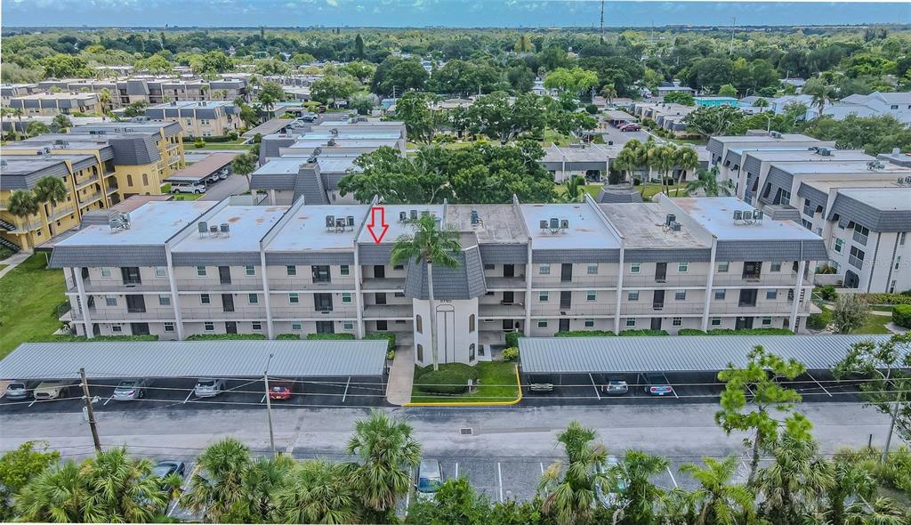 An aerial view of a multi-story apartment building with covered parking and surrounding landscaping — 8765 BARDMOOR BOULEVARD UNIT 304, SEMINOLE, FL