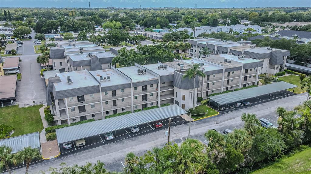 An aerial view of a multi-story apartment complex with covered parking spaces and surrounding landscaping — 8765 BARDMOOR BOULEVARD UNIT 304, SEMINOLE, FL