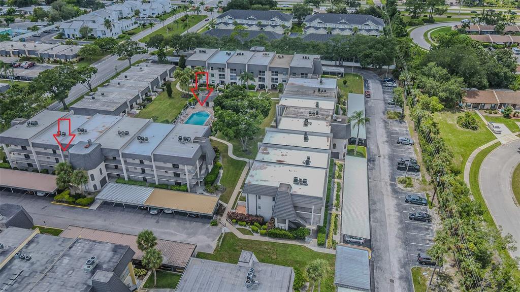 An aerial view shows multi-story apartment buildings with a central swimming pool and covered parking — 8765 BARDMOOR BOULEVARD UNIT 304, SEMINOLE, FL