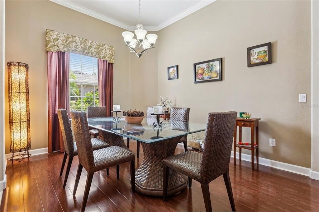 A dining room features a glass-topped table, woven chairs, hardwood floors, and a chandelier — 2876 SANDY CAY STREET, CLERMONT, FL