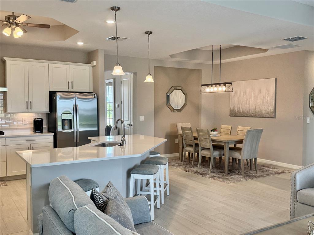 An open-concept kitchen with a breakfast bar and dining area featuring light-colored cabinetry and tile — 19146 CHERRYSTONE WAY, LAKEWOOD RANCH, FL