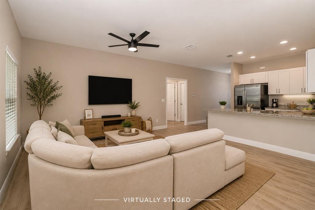 A living room with a sectional sofa, television, and an open kitchen with white cabinets — 2841 NW 45TH PLACE, CAPE CORAL, FL